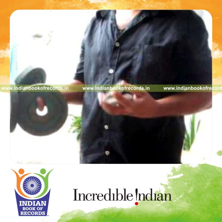 individual performing charlier card cuts while holding weight plates for record in Indian Book of Records