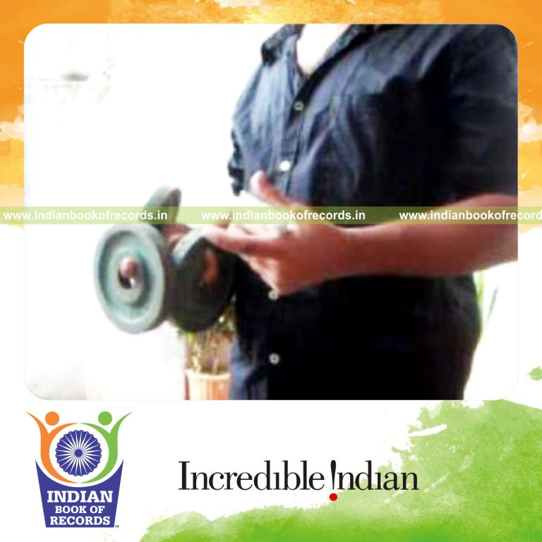 individual performing thumb card cuts while holding weight plates for record in Indian Book of Records