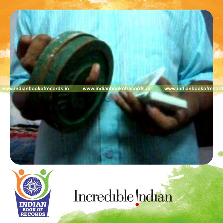 individual performing charlier card cuts while holding weight plates on pinky finger for record in an Indian Book of Records