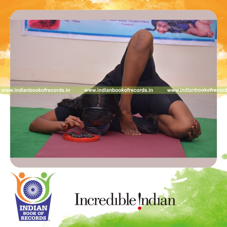 individual female solving brainvita while holding ekapatha vamadeva vama hasta kanda perundasana yoga pose blindfolded for Indian Book of Records
