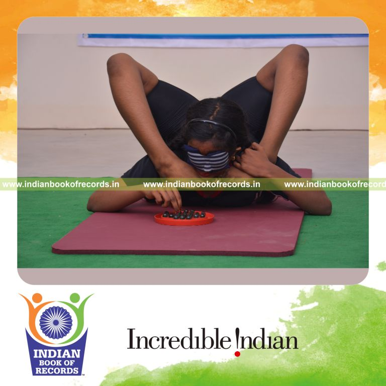 individual female solving brainvita while holding viparitha kanda perundasana blindfolded for Indian Book of Records