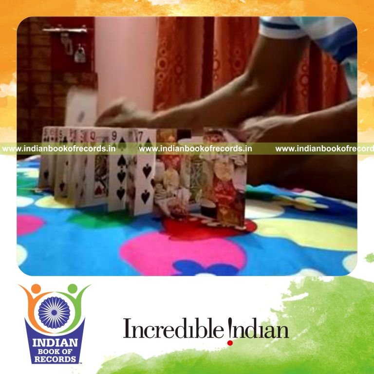 individual setting up and toppling playing card domino chain quickly for record in Indian Book of Records
