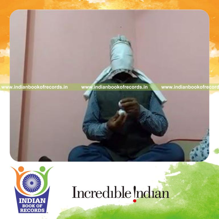 individual balancing golf ball on another golf ball in hand while blindfolded for record in Indian Book of Records