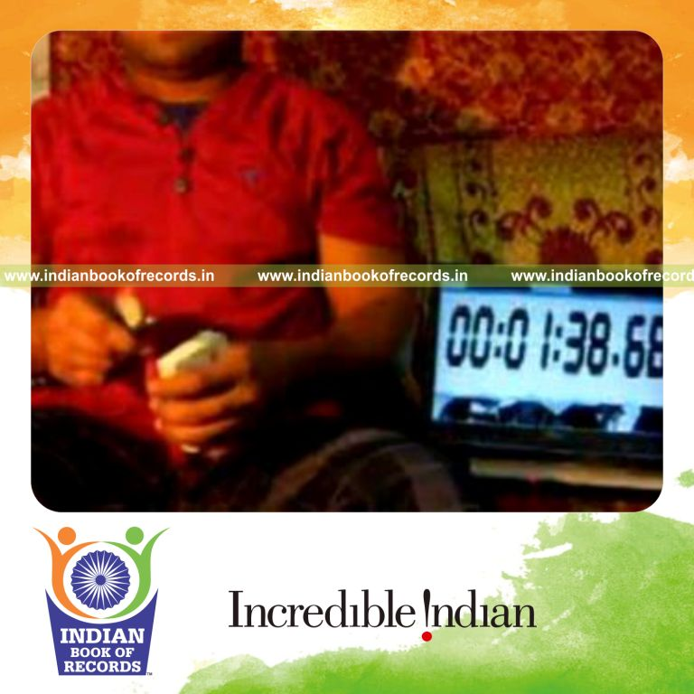 individual performing triangle card cut while spinning toothbrush on pen for record in Indian Book of Records