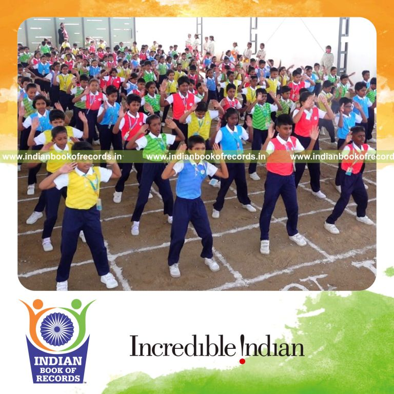 A large group performing jumping jack exercises together at a single venue for the Indian Book of Records