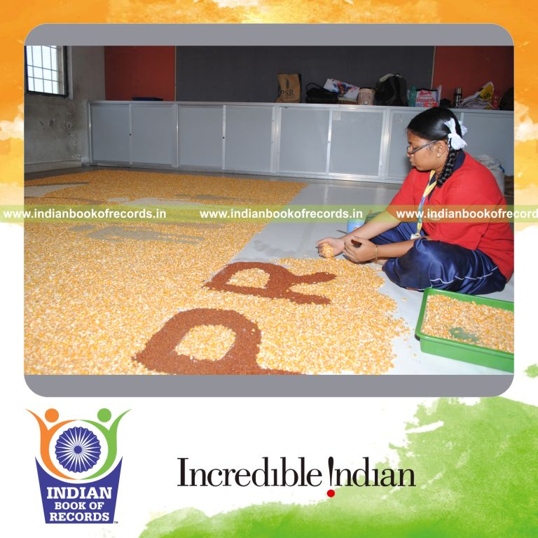 young female creating large mosaic using grains for record in Indian Book of Records