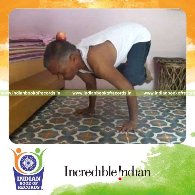 individual balancing apple on head while holding crow pose for record in Indian Book of Records