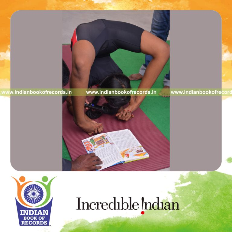 individual female performing backward reading while holding viparitha chakrabandasana blindfolded for Indian Book of Records