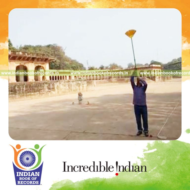 individual walking backward while balancing broom on chin for record in Indian Book of Records
