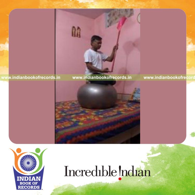 individual balancing broom on finger while balancing on exercise ball for record in Indian Book of Records