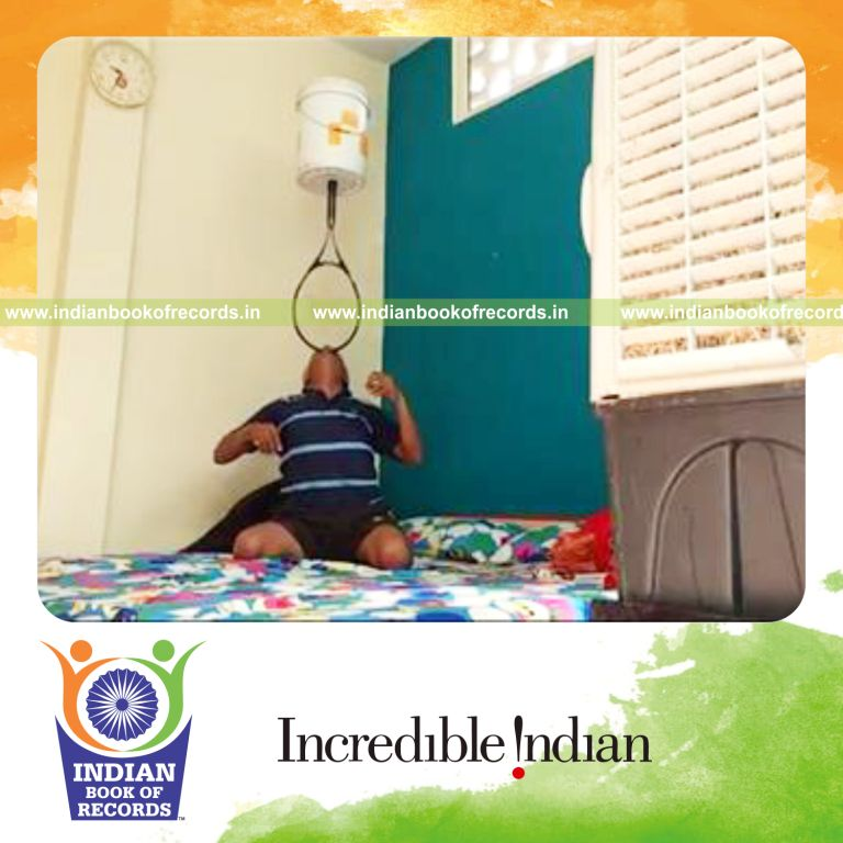 individual balancing five gallon bucket on tennis racquet on chin while kneeling for record in Indian Book of Records