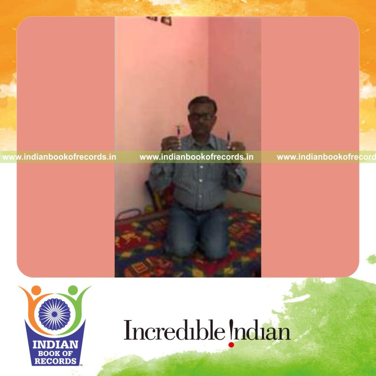 individual balancing playing card on pen on both hands while holding thunderbolt pose for record in Indian Book of Records