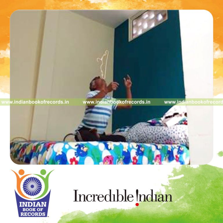 individual balancing clothes hanger on nose while sitting cross legged for record in Indian Book of Records