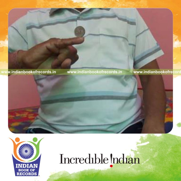 individual balancing coin vertically on right pinky finger for record in Indian Book of Records