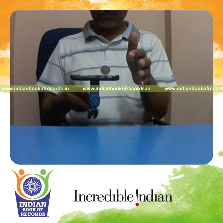 individual balancing coin vertically on smartphone placed on hammer held in hand for record in Indian Book of Records