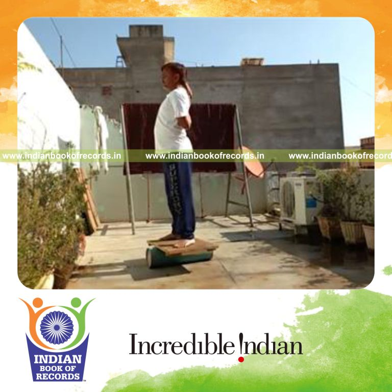 individual holding cow face pose while standing on rola bola for record in Indian Book of Records
