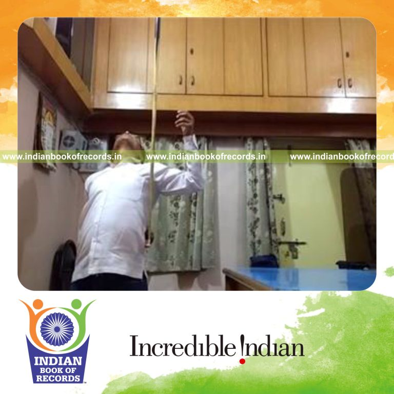 individual balancing cue stick on index finger behind back for record in Indian Book of Records