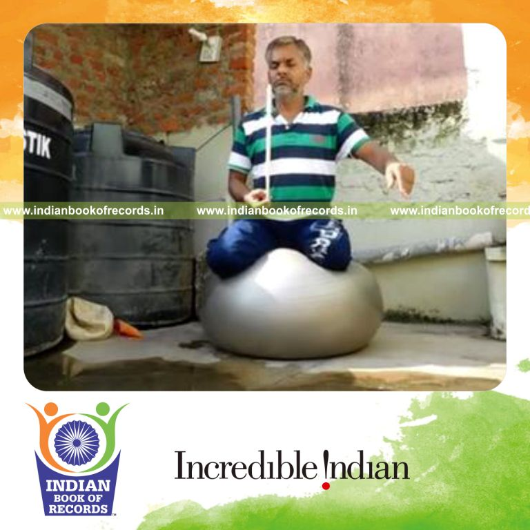 individual balancing drumstick on finger while balancing on exercise ball for record in Indian Book of Records