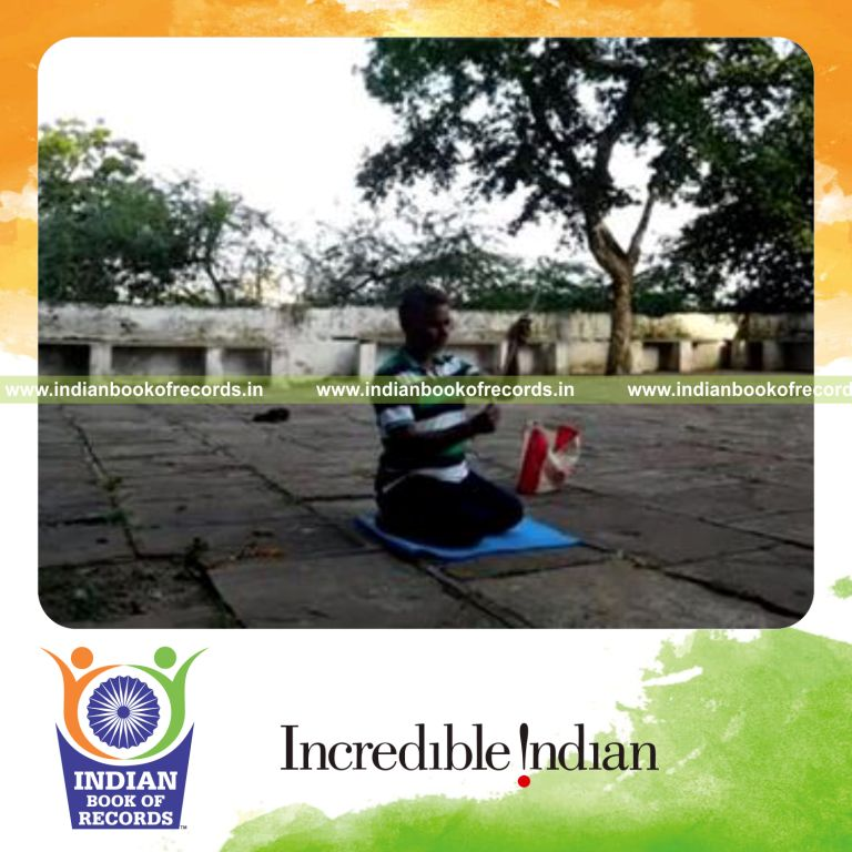 individual balancing drumstick on thumb while kneeling for record in Indian Book of Records