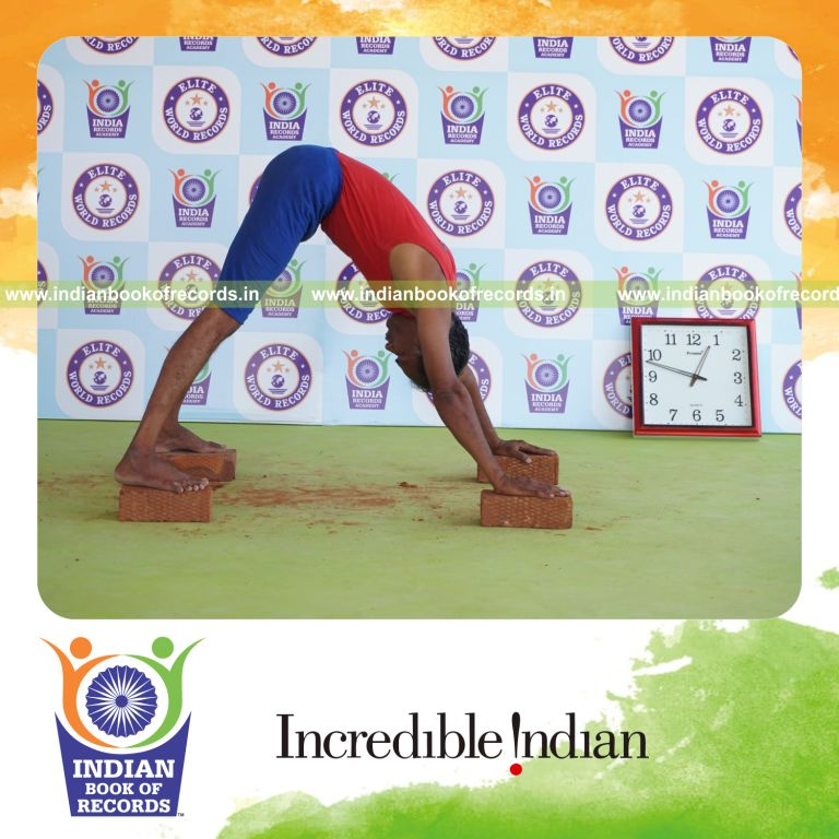 individual holding adho mukha svanasana yoga pose on bricks for record in Indian Book of Records