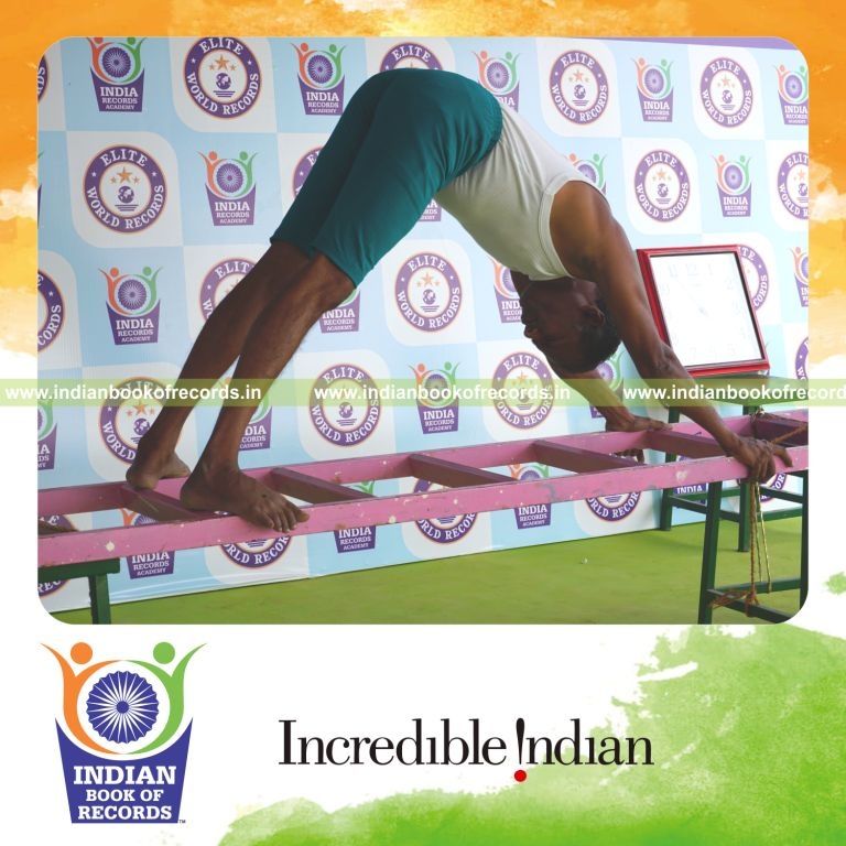 individual holding adho mukha svanasana yoga pose on a ladder for record in Indian Book of Records
