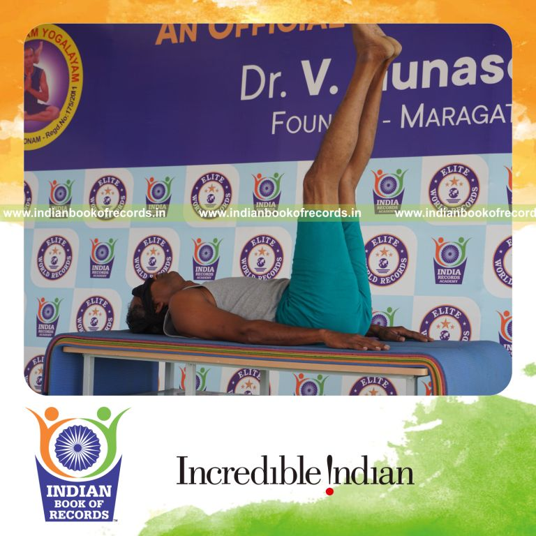 individual holding ardha halasana yoga pose blindfolded on a table for record in Indian Book of Records