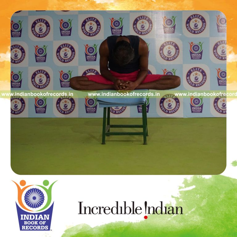 individual holding baddha konasana yoga pose on a stool for record in Indian Book of Records