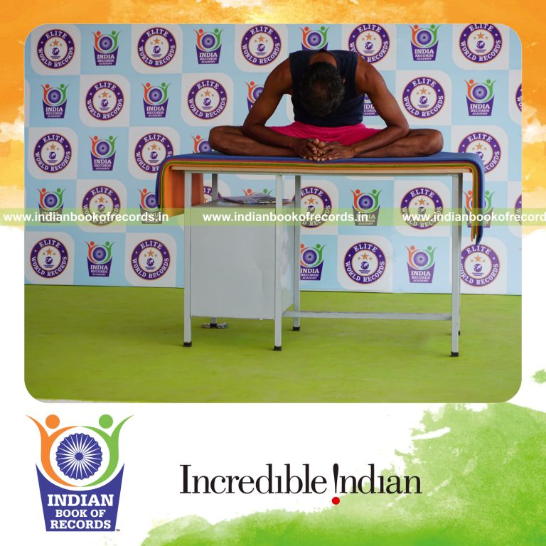 individual holding baddha konasana yoga pose on a table for record in Indian Book of Records