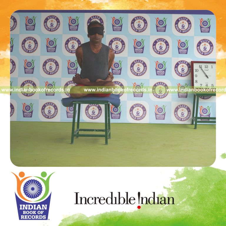 individual holding baddha padmasana yoga pose blindfolded on a stool for record in Indian Book of Records
