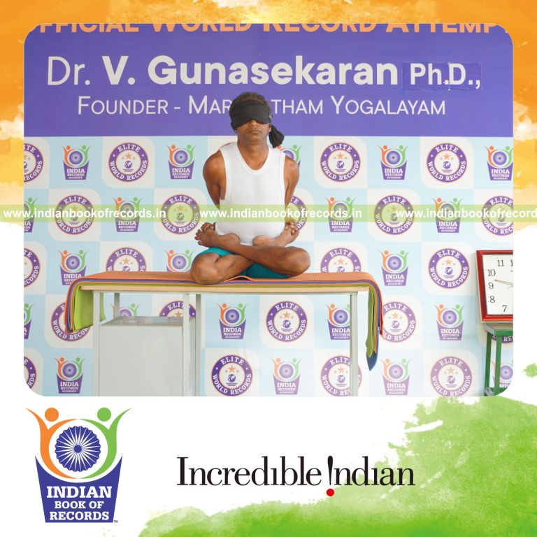 individual holding baddha padmasana yoga pose blindfolded on a table for record in Indian Book of Records