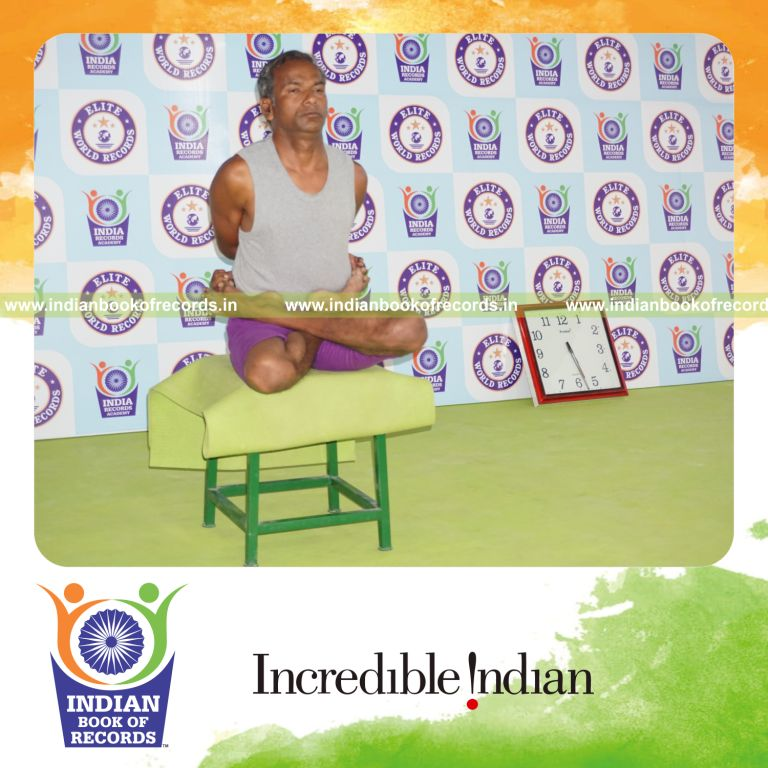 individual holding baddha padmasana yoga pose on a stool for record in Indian Book of Records