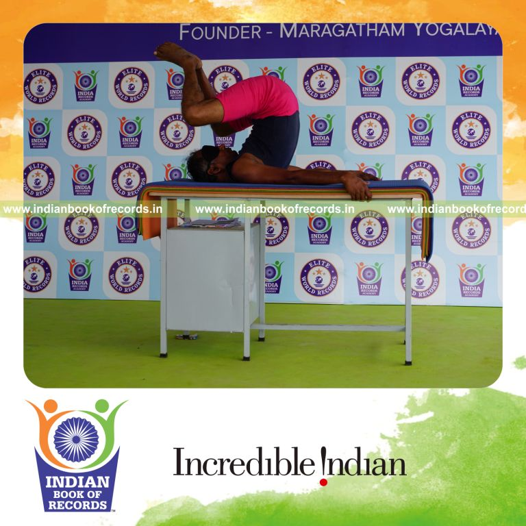 individual holding baddha salamba sarvangasana yoga pose blindfolded on a table for record in Indian Book of Records