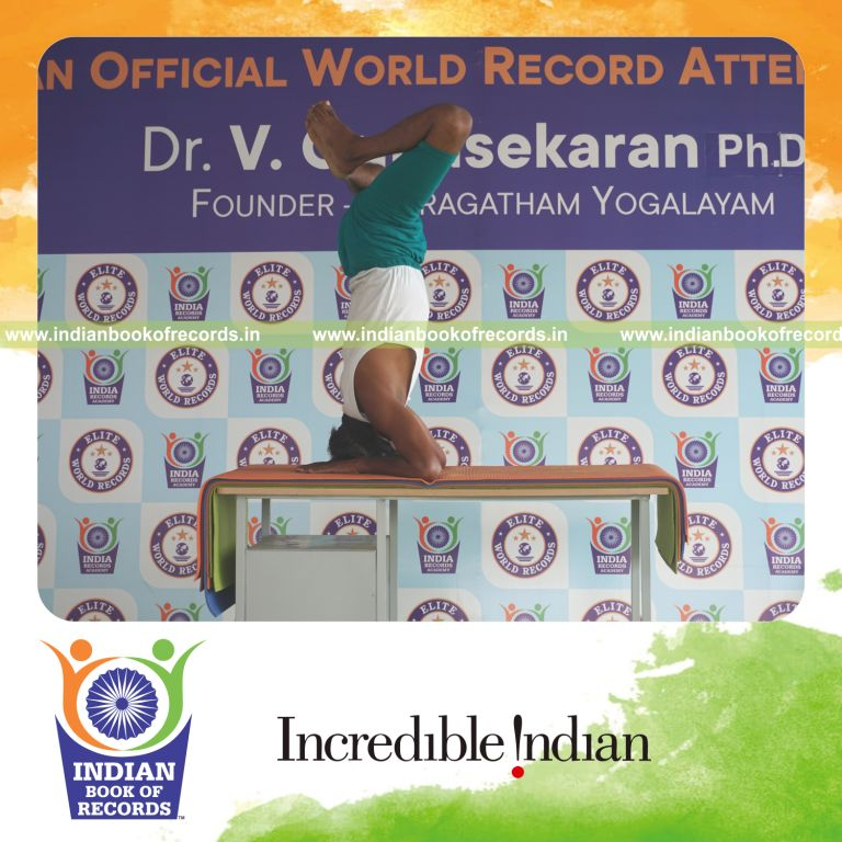 an individual holding baddha salamba sirsasana yoga pose blindfolded on a table continuously for the longest duration with stability and control for a record in Indian Book of Records
