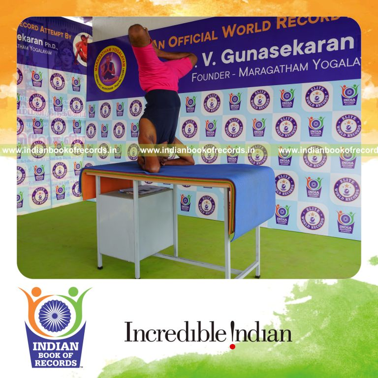 individual holding baddha sirasasana yoga pose on a table for record in Indian Book of Records