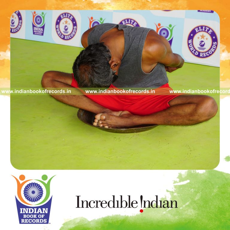individual holding badha goburasana yoga pose blindfolded on a brass plate for record in Indian Book of Records