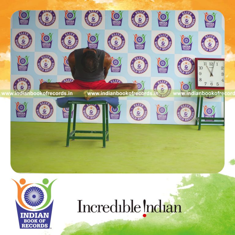 individual holding badha goburasana yoga pose blindfolded on a stool for record in Indian Book of Records