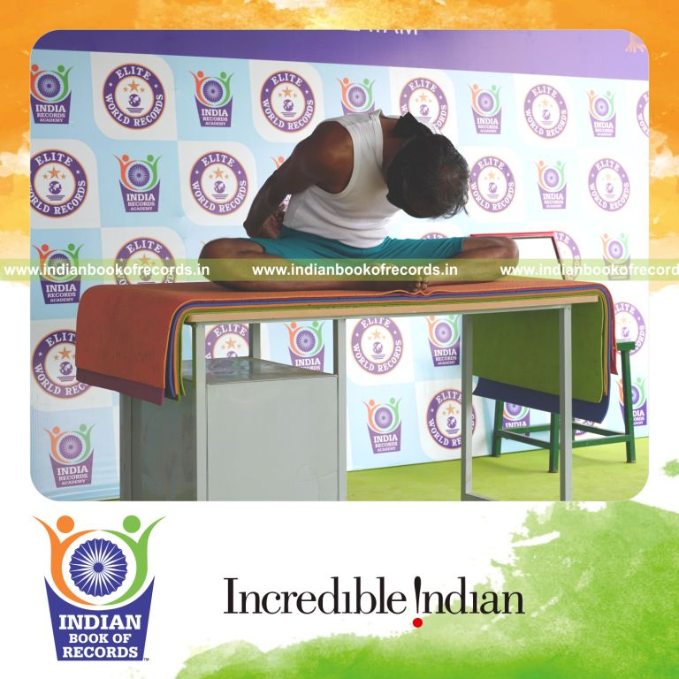 individual holding badha goburasana yoga pose blindfolded on a table for record in Indian Book of Records