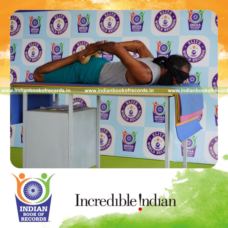 individual holding bhekasana yoga pose blindfolded on a table for record in Indian Book of Records