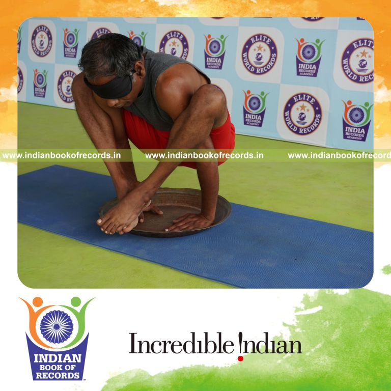 individual holding bhujapidasana yoga pose blindfolded on a brass plate for record in Indian Book of Records