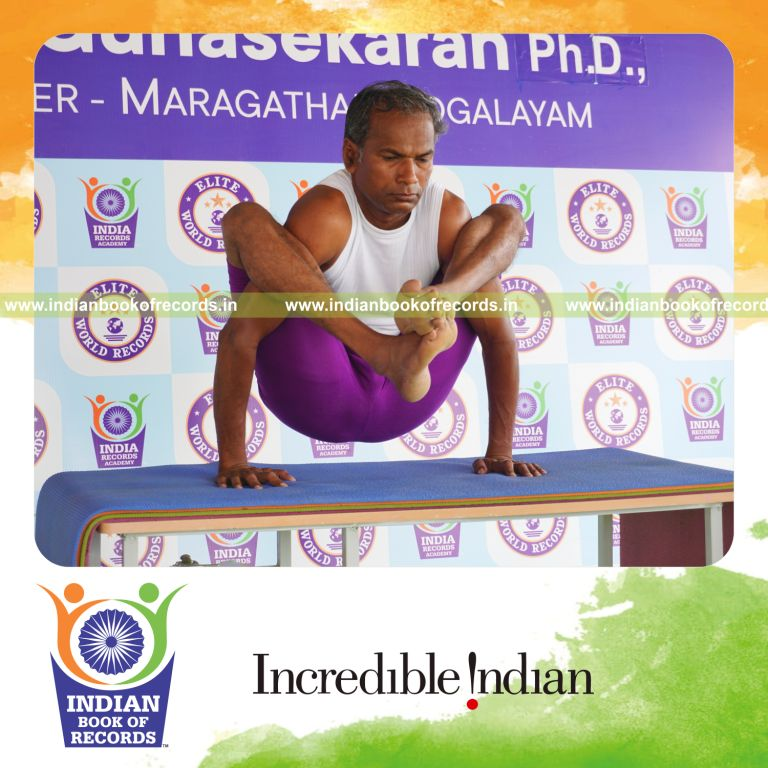 individual holding bhujapidasana yoga pose on a table for record in Indian Book of Records