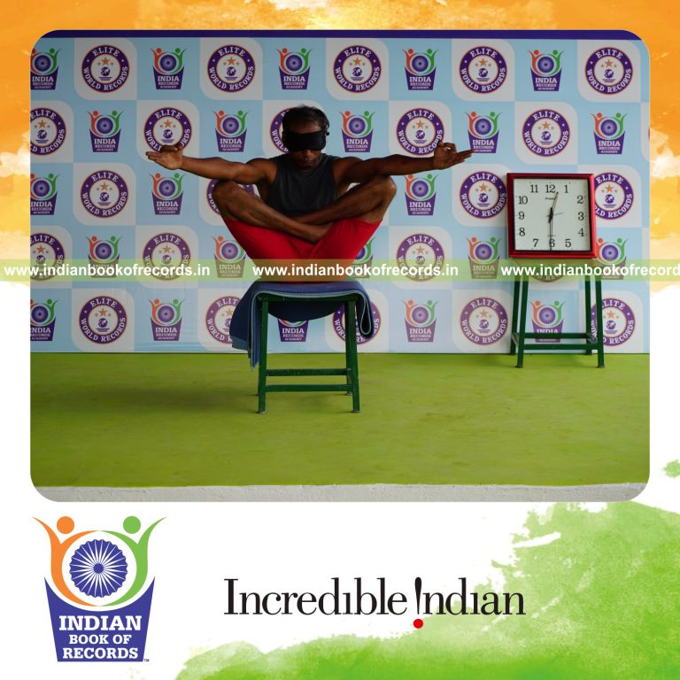 individual holding chinmudra thulangasana yoga pose blindfolded on a stool for record in Indian Book of Records