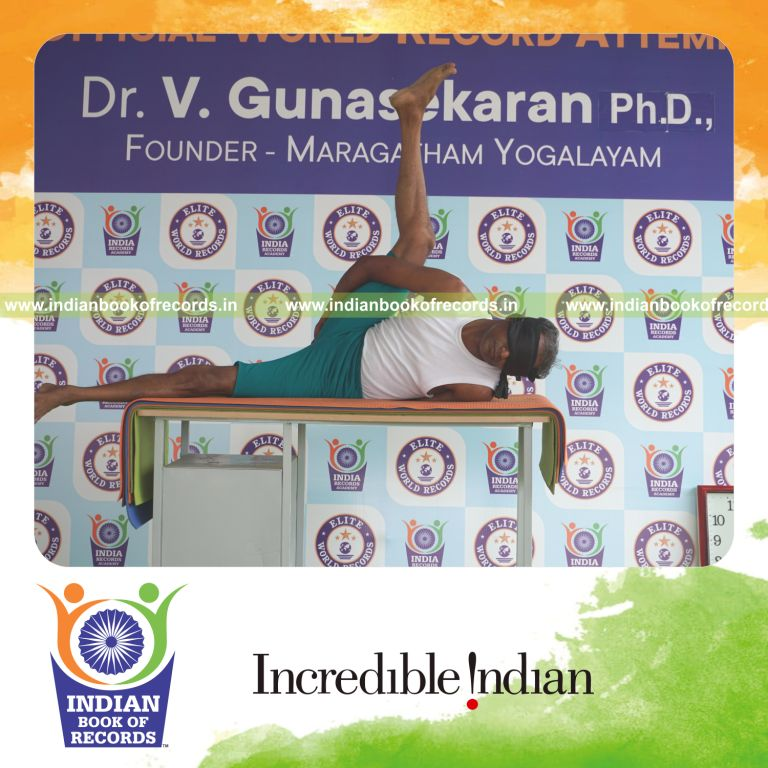 an individual holding daksina ananda ardha matsyendrasana yoga pose blindfolded on a table continuously for the longest duration with balance and control for a record in Indian Book of Records