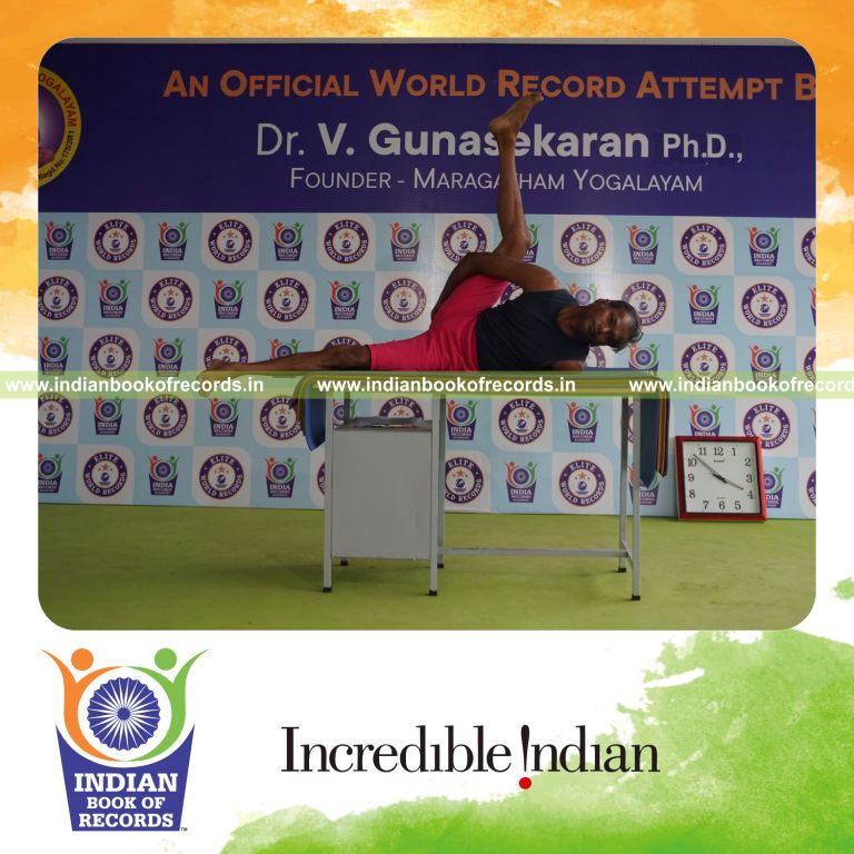 individual holding daksina ananda ardha matsyendrasana yoga pose on a table for record in Indian Book of Records