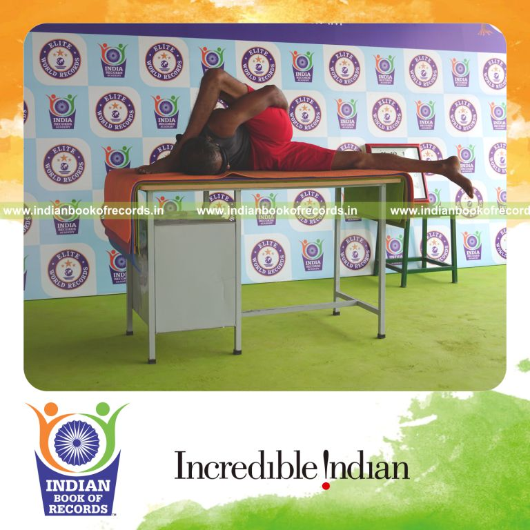 individual holding daksina ardha astavakrasana yoga pose blindfolded on a table for record in Indian Book of Records