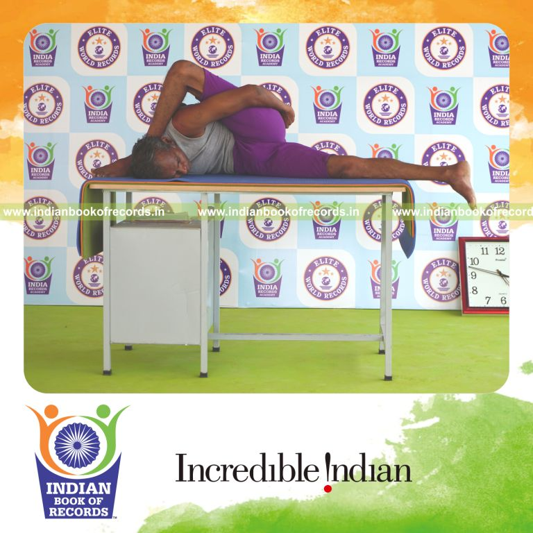 individual holding daksina ardha astavakrasana yoga pose on a table for record in Indian Book of Records