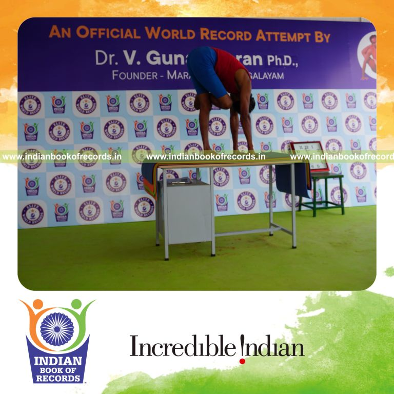 individual holding daksina ardha baddha padmottasana yoga pose blindfolded on a table for record in Indian Book of Records
