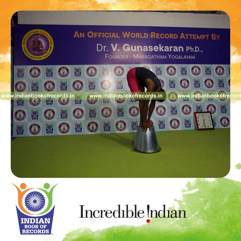 individual holding daksina ardha baddha padmottasana yoga pose on a bucket for record in Indian Book of Records