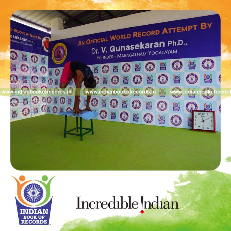 individual holding daksina ardha baddha padmottasana yoga pose on a stool for record in Indian Book of Records
