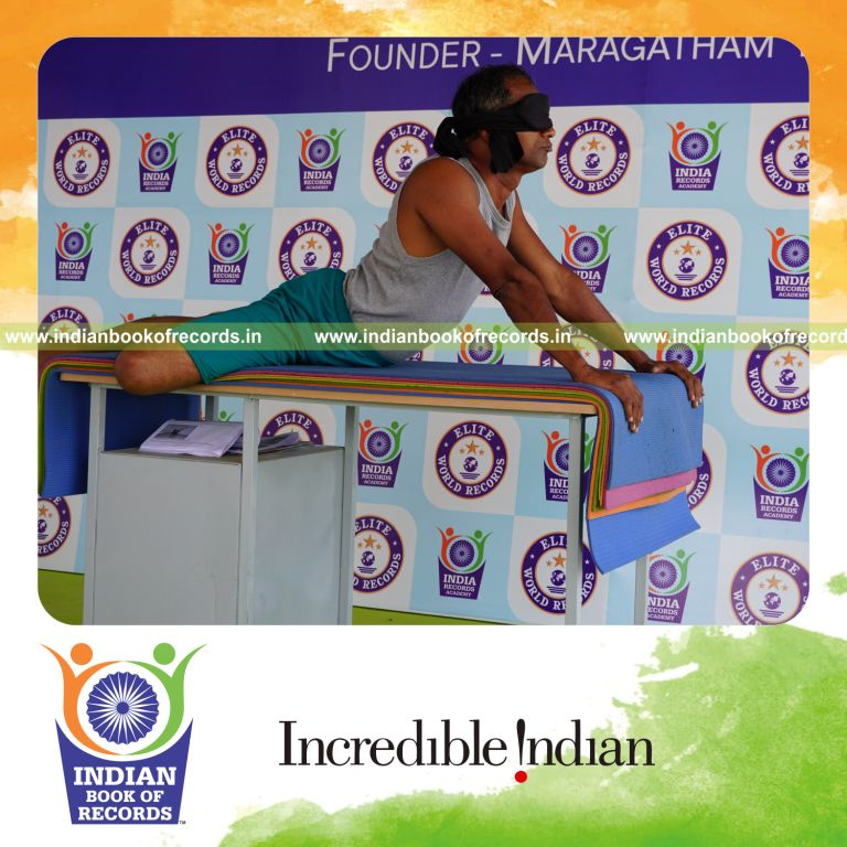 individual holding daksina ardha bhujangasana yoga pose blindfolded on a table for record in Indian Book of Records