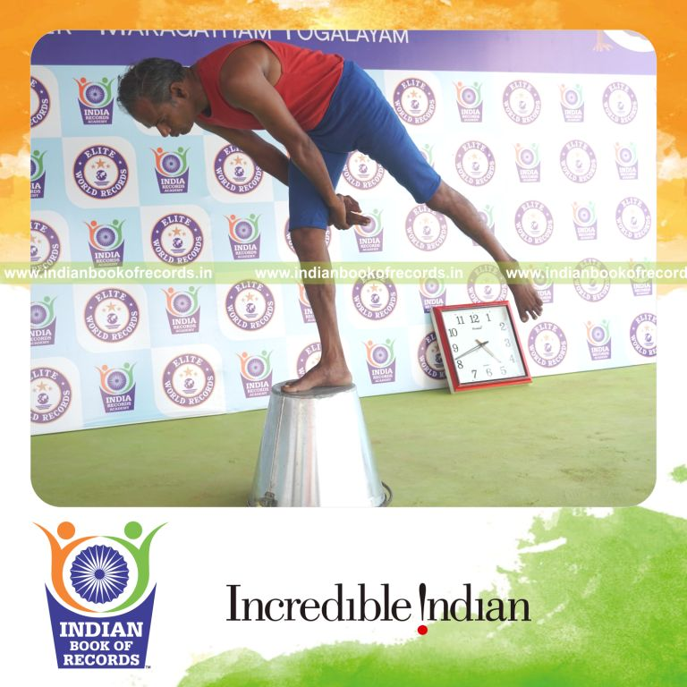 individual holding daksina ardha chandra virabhadrasana yoga pose on a bucket for record in Indian Book of Records